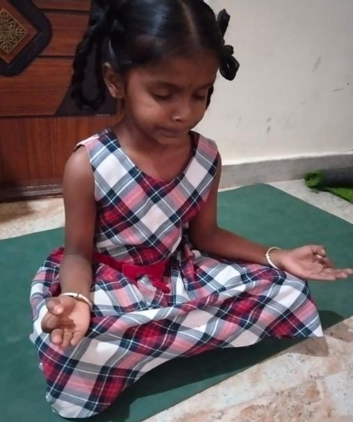 A young girl sitting cross-legged in meditation with eyes closed