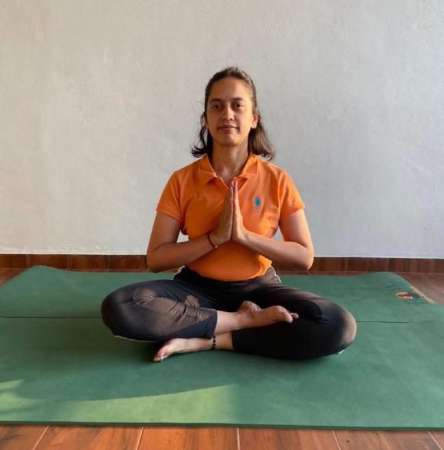 Priya Balse sitting in lotus pose with hands in prayer