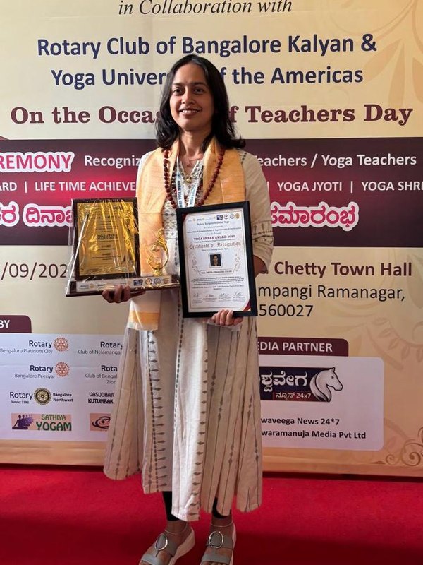Priya Balse holding the Yoga Shree Award trophy and certificate of recognition at the Rotary Bangalore Global Yoga Teachers' Day ceremony